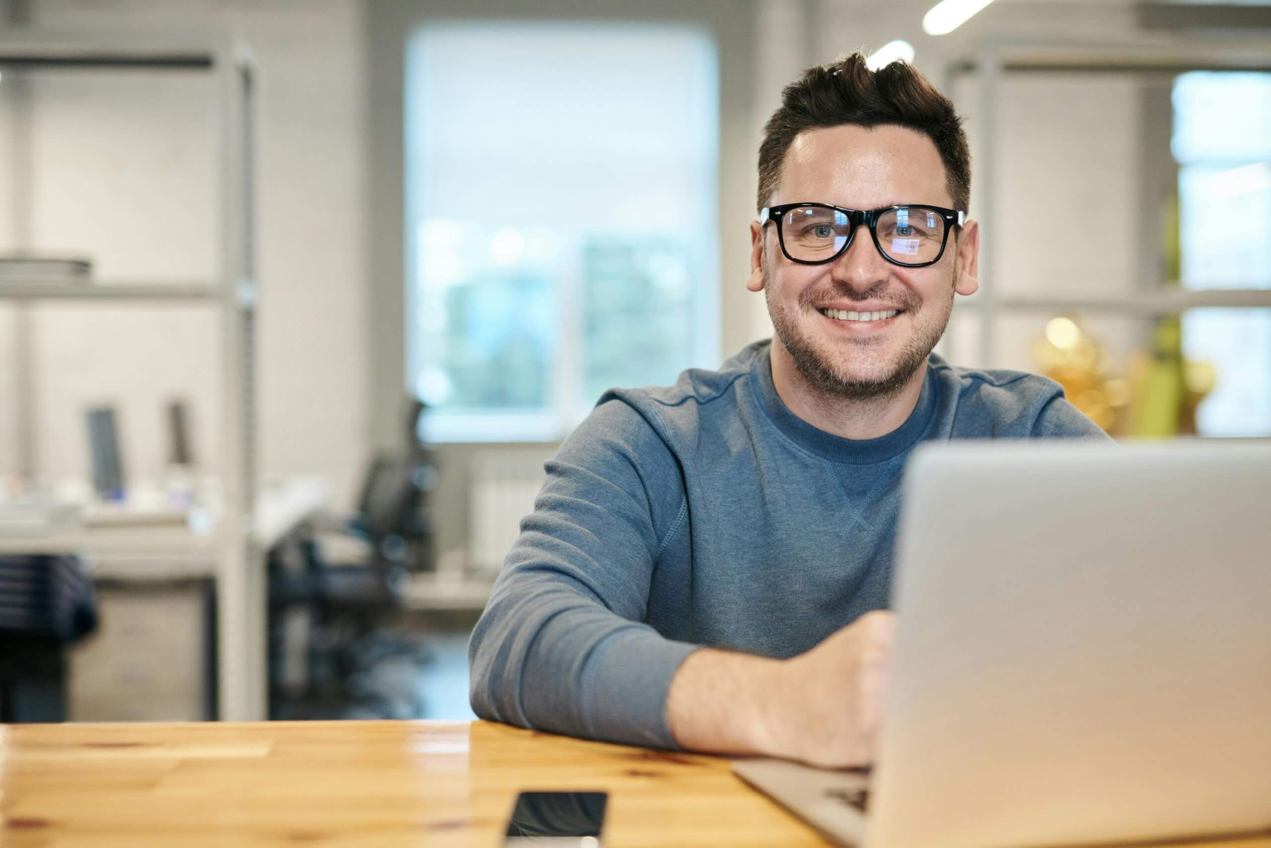 Man at his laptop smiling: Employers' Guide to the New Flexible Working Law 2024